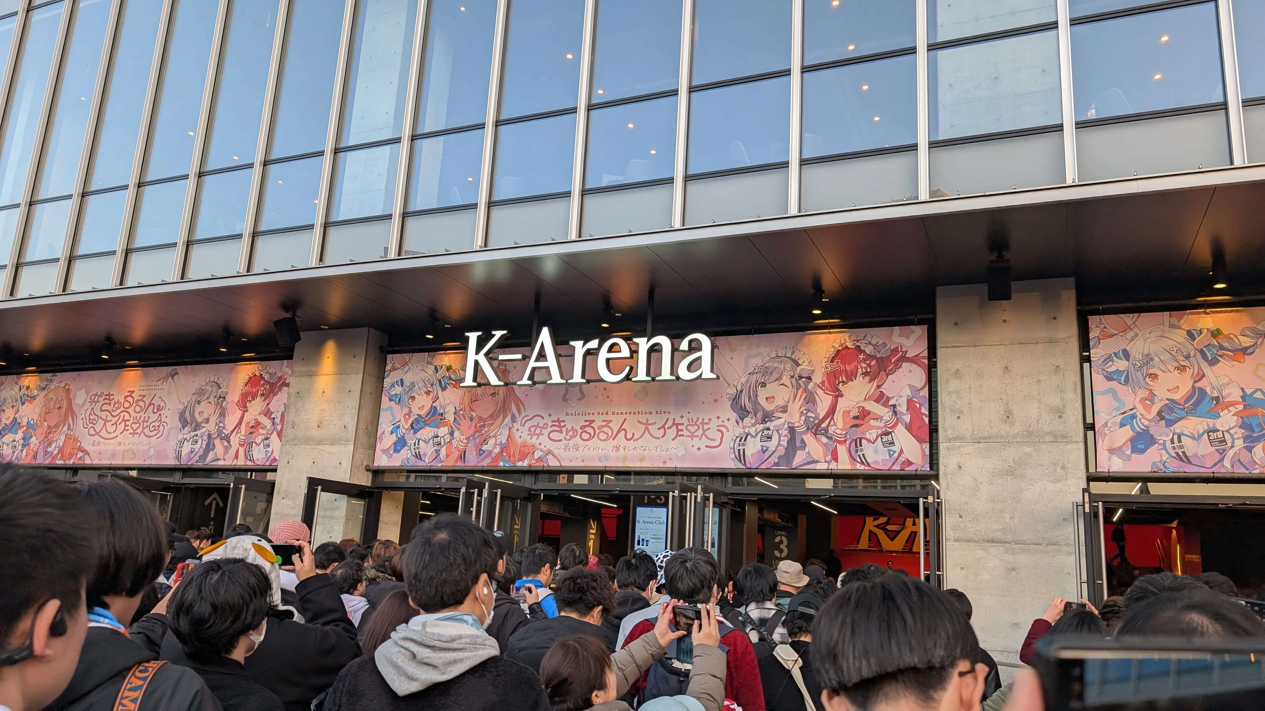 Kアリーナ横浜の入口。きゅるるん大作戦の横断幕が掲げられ、入場待ちの人々が並んでいる。