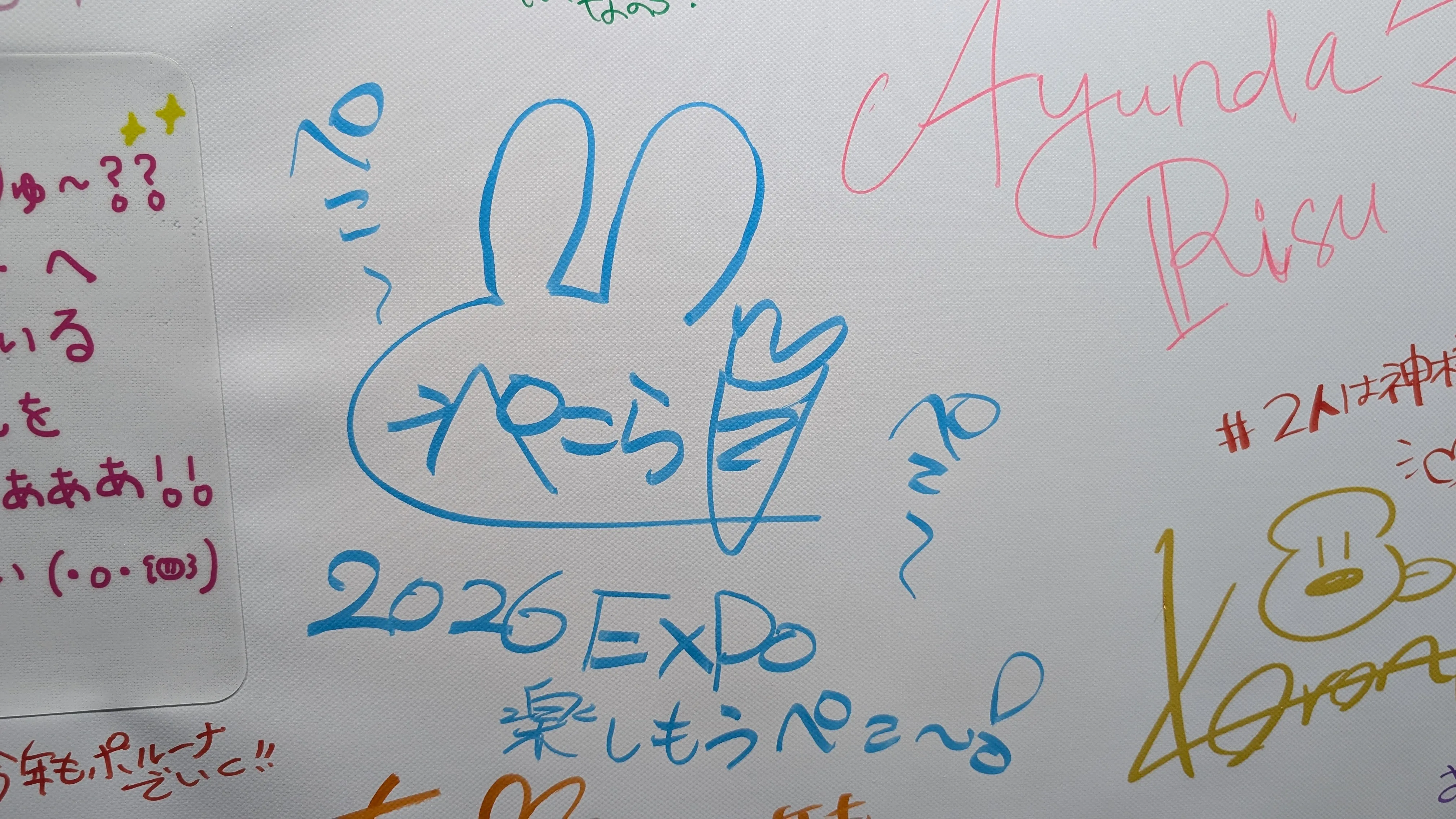 サインボード（ぺこら「2026 EXPO 楽しもうぺこ～♪」・Ayunda Risu のサイン）