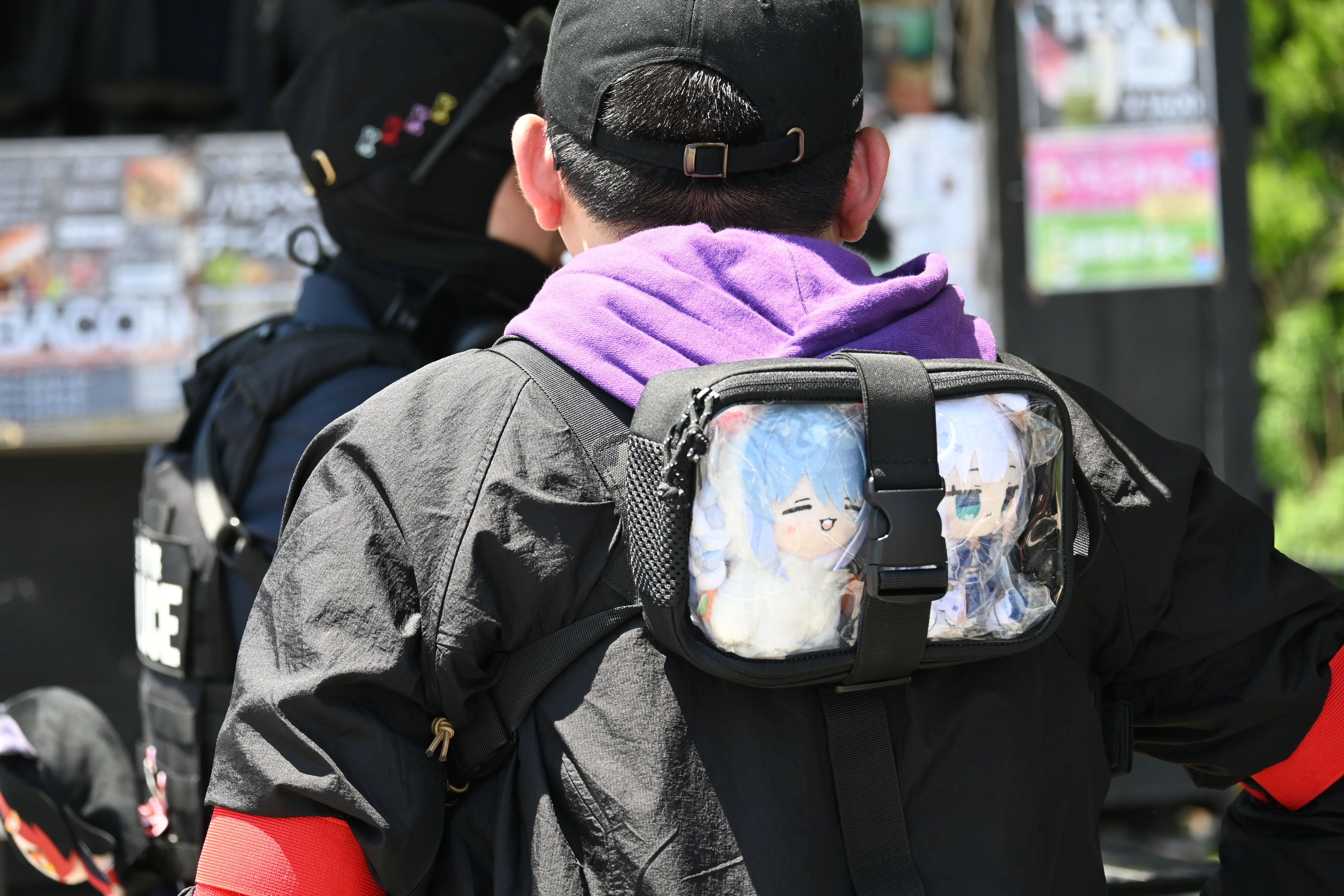 背中にホロライブキャラクターのぬいぐるみポーチを付けた参加者の後ろ姿